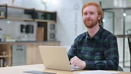 Redhead Man with Laptop Shaking Head in Approval, Yes 