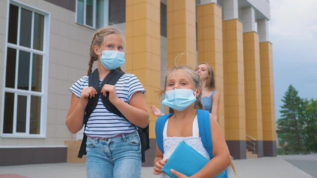 Schoolchildren wear safety mask on face. Children go back to school. Schoolchildren wear health safety mask during COVID19. Children go in masks in the court of school.