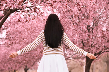 Young woman in park with blooming trees. Spring look