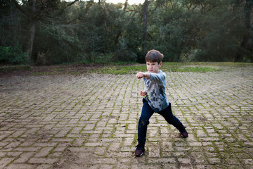 Un niño practicando artes marciales en el bosque.