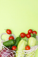 Ripe juicy red tomatoes, green cucumbers and zucchini in a string bag.