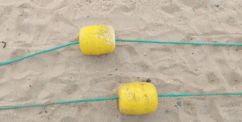 Plastic buoys fencing for the beach area against a background of sand.