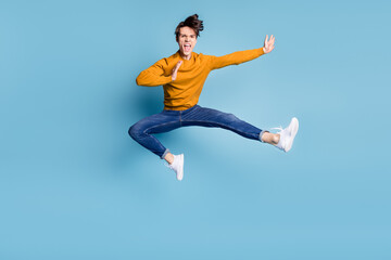 Full body photo of impressed brunet millennial guy fight wear sweater jeans isolated on blue color background