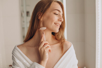 Woman doing self massage with rose quartz face roller