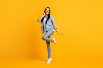 Full size photo of adorable satisfied young girl dancing raise knee toothy smile isolated on yellow color background