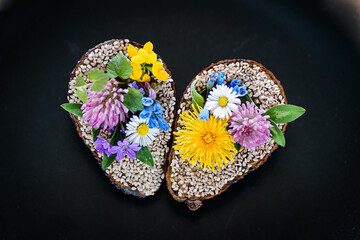 vegan halved avocado heart on a plate decorated with daisy, dandelion, leafs and meadow flowers for...