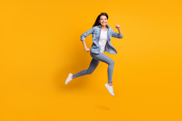 Full size profile photo of cool optimistic brunette lady run jump wear blue shirt jeans sneakers isolated on yellow background