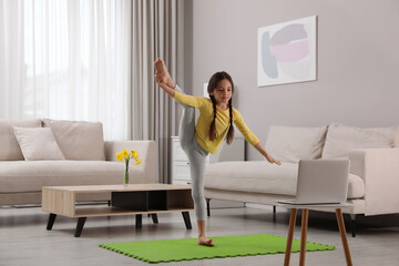 Cute little girl taking online dance class at home