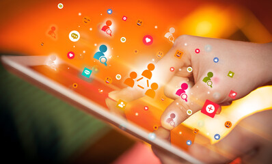 Close-up of a hand using tablet with social media icons
