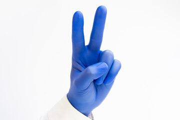 Hand in blue latex Glove raising two fingers up on hand it is shows peace strength fight or victory symbol