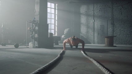 Athlete doing push ups in gym. Man making fitness training in loft building