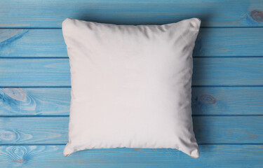 Blank soft pillow on light blue wooden background, top view