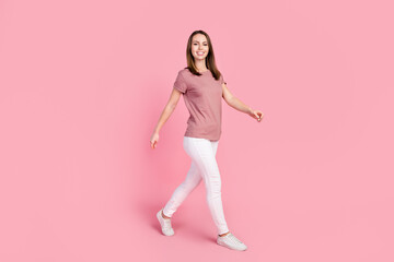 Fototapeta na wymiar Full length body size view of attractive cheerful content slender girl walking isolated over pink pastel color background