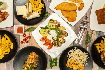 Mediterranean dishes and burritos, chicken schnitzel, shrimp rice, cherry tomatoes, curry noodles, French fries, forks, wild asparagus, grilled vegetables