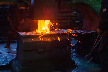 close-up picture of hot steel manual forging process with big mechanical hammer machine