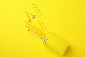 Holder with different stationery on yellow background