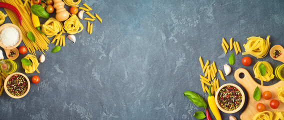 Italian pasta, tomatoes, basil herbs and spices over dark background. Italian cuisine concept