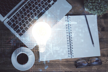 Bulb drawing over computer on the desktop background. Top view. Double exposure. Idea concept.