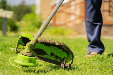 A close up of a young man with a lawnmower caring for the grass in the backyard.