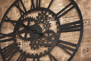 gear-shaped wall clock on wallpaper with motifs of old newspaper