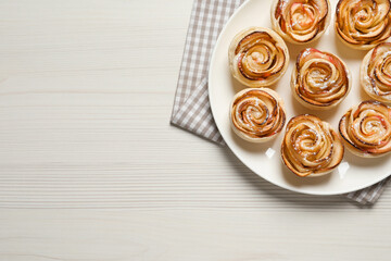 Freshly baked apple roses on white wooden table, top view. Space for text