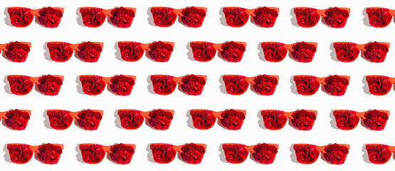 Creative pattern made of red sunglasses with rose buds on white background. Summer fashion concept. Top view. Flat lay