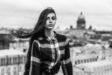 portrait of an Armenian girl with fluttering long black hair in a checkered shirt and jeans on a...