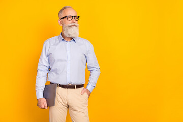 Photo of serious attractive age gentleman wear blue shirt glasses holding device looking empty space isolated yellow color background