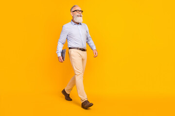 Fototapeta premium Photo of lucky cute mature man dressed formal outfit spectacles holding gadget walking empty space isolated yellow color background