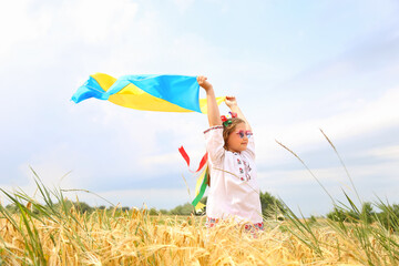 Yellow and blue flag of Ukraine in the hands of a beautiful girl in an embroidered shirt and a wreath with ribbons. Child in a wheat field. Independence Day of Ukraine, Flag , Constitution, Embroidery