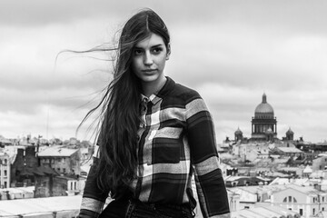 portrait of an Armenian girl with fluttering long black hair in a checkered shirt and jeans on a...