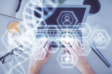 Double exposure of man's hands typing over computer keyboard and DNA hologram drawing. Top view. Medical education concept.