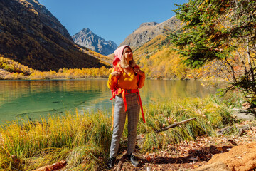 Happy woman with backpack at lake in the autumnal mountains.