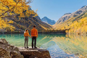 Happy couple at crystal lake in the autumnal mountains. Mountain lake and hikers