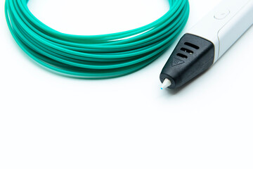 3D printing pen and rolled green PLA filament on the white background