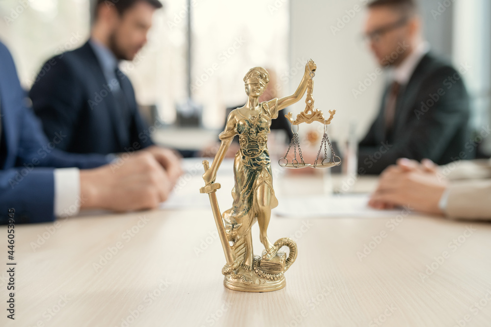 Aufkleber close-up of figure of justice standing on the table with group of lawyers sitting at meeting in the 