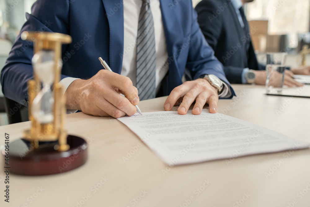 Aufkleber close-up of businessman sitting at the table and signing a contract during a business meeting at off