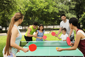 Happy families playing ping pong in park - obrazy, fototapety, plakaty