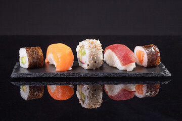 Assorted sushi served on slate plate on dark background. Japanese food.