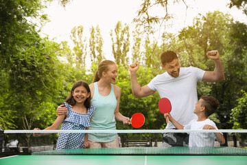 Happy family playing ping pong in park