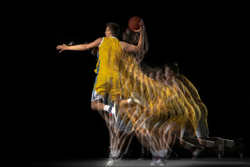 Young caucasian basketball player in motion and action isolated on dark background with stroboscope...