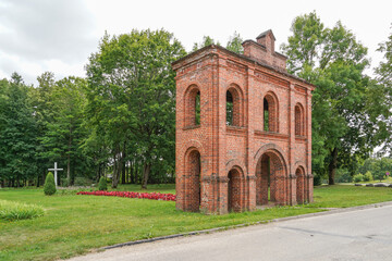 Fototapeta na wymiar Old Catholic Church red brick gates in city Akniste, Latvia. Aknistes visual identity symbol.