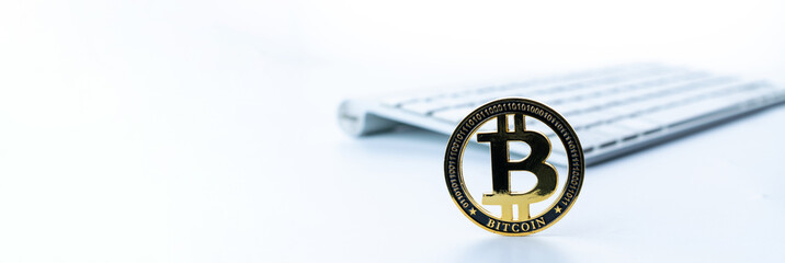 Fototapeta premium Bitcoin wallet. Golden Bit Coin virtual cryptocurrency or blockchain technology. Gold Crypto currency BTC with keyboard on white background. Investing in virtual assets, Bull market trend concept.