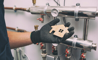 Wooden flat house in plumber's hand in protection gloves