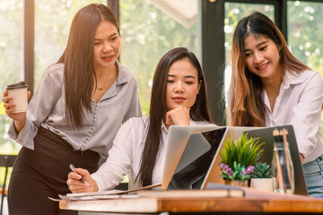 Group of asian young business woman working and communicating while sitting at the office desk together with charts and graphs banner, double exposure successful teamwork,business planning concept.