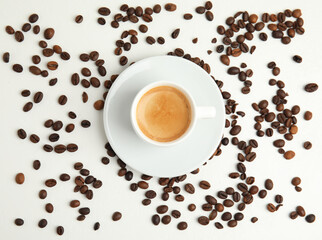 Cup of hot aromatic espresso and roasted beans on white table, flat lay