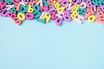 Lots of scattered multicolored letters on blue background . Learning to read, alphabet.