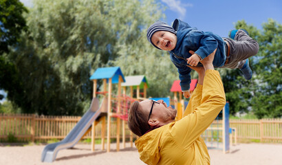 family, childhood, fatherhood, leisure and people concept - happy father and little son playing and having fun over children's playground background