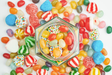 Hexagonal jar full of jelly candies with scattered sweets in the background.