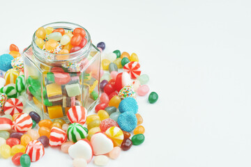 Jar with sweets and candies around on a white background.